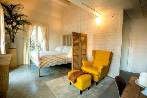 a bedroom with a bed and a yellow chair at Sasaràl Suites in Cesena