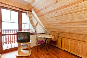 a room with a television and a table with chairs at Studia Aurora in Demanovska Dolina