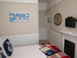 a bedroom with a bed with a fireplace and a mirror at Blyth Hotel in Southwold