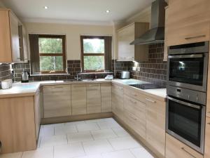 a large kitchen with wooden cabinets and appliances at Woodlands in Aviemore