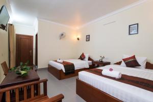 a hotel room with two beds and a television at Chamraoen’s Home in Siem Reap
