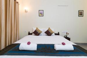 Un dormitorio con una gran cama blanca con dos almohadas. en Chamraoen’s Home, en Siem Reap