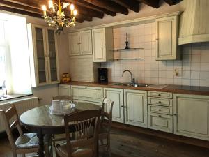 a kitchen with white cabinets and a table and a sink at La Ferme du Grand Frêne in Naomé