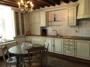 a kitchen with white cabinets and a table and a sink at Ferme du Grand Frêne in Naomé