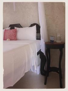 a bed with a white comforter and a side table at Andavelo House in Lamu