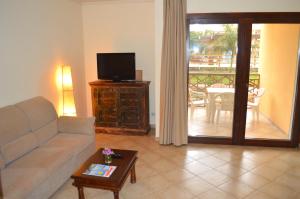 salon z kanapą i telewizorem oraz balkonem w obiekcie Apartment | in Tropical Resort | pool | close to beach w mieście Santa Maria