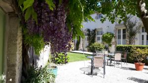 d'une terrasse avec des chaises et une table ornée de fleurs violettes. dans l'établissement Hôtel du Donjon, à Aulnay