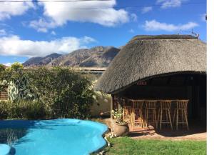 a house with a thatch roof and a swimming pool at John Montagu Accommodation in Montagu