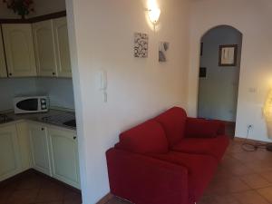 a living room with a red couch and a kitchen at Appartamenti Le Gemme in Palau