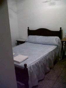 a bedroom with a bed with a wooden head board at Hostal Medina in Olvera