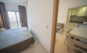 a room with a bed and a table and a kitchen at Apartamentos Embat in Can Pastilla