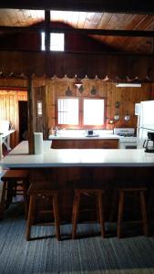a kitchen with a large white counter and wooden tables at Log Cottage on Blue Lake in Kalkaska
