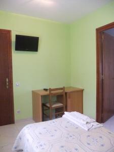 a bedroom with a bed and a desk and a television at Pensió L'Estada in Sant Joan les Fonts