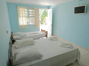 two beds in a room with blue walls and a window at Big Valley Hotel Fazenda in Serra Negra