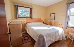 a bedroom with a bed with a white blanket on it at Cavendish Lodge & Cottages in Cavendish