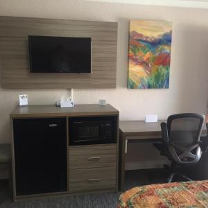 Habitación de hotel con escritorio, TV y silla. en Death Valley Inn & RV Park en Beatty