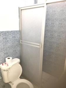 uma casa de banho com um WC e uma cabina de duche em vidro. em HOTEL SUNSHINE AIRE ACND y WIFI ZONE em Tonsupa