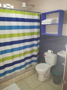 a bathroom with a toilet and a shower curtain at Puerto Vargas lodge in Cahuita