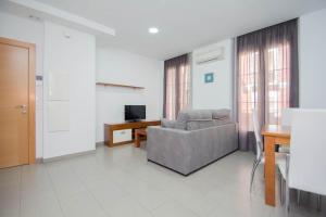 een woonkamer met een bank en een televisie bij EnjoyGranada GRAN VIA 1B & Parking opcional in Granada
