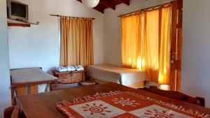 a room with two beds and a table and a window at Cabañas Los Gauchitos in La Falda +36 photos