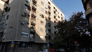 un edificio de apartamentos alto con coches estacionados frente a él en Apartment Elza, en Belgrado