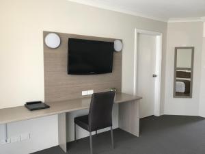 een kamer met een bureau en een televisie aan de muur bij Acacia Motor Lodge in Coonabarabran
