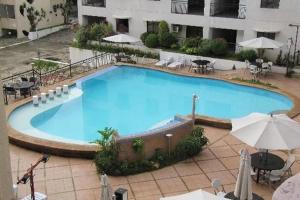 a large blue swimming pool with tables and umbrellas at CLOCKWORKORANGE Luxury Suites in Mactan