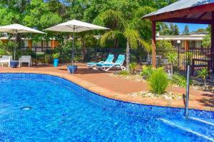 a swimming pool with two chairs and an umbrella at River Country Inn in Moama