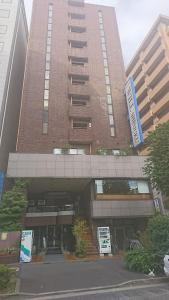 Residence Hotel Will Shinjuku في طوكيو: مبنى طويل وبه مرآب للسيارات أمامه