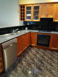 a kitchen with wooden cabinets and a stainless steel dishwasher at King Street Apartments in Warrnambool