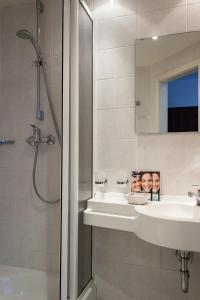 ein Bad mit einem Waschbecken, einer Dusche und einem Spiegel in der Unterkunft Landhotel Alt-Jocketa in Pöhl