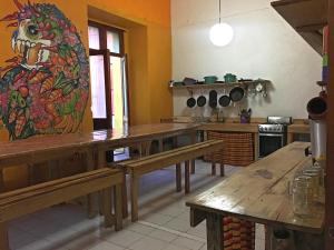 a kitchen with wooden tables and a painting on the wall at Iguana Hostel Oaxaca in Oaxaca City