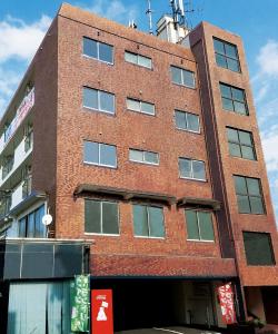 a red brick building with windows on a street at Weekly Hotel Kokura in Kitakyushu