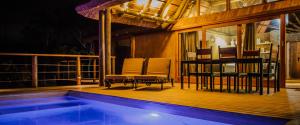 a deck with chairs and a swimming pool at night at Aloe Ridge in Swellendam