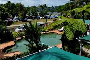 a swimming pool with palm trees and a parking lot at Waterfront Terraces in Cairns