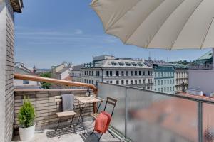 a balcony with chairs and a table and an umbrella at JT's Apartments Opletalova str. in Prague