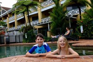 a boy and a girl laying next to a swimming pool at Waterfront Terraces in Cairns