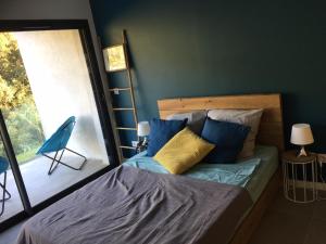 sypialnia z łóżkiem z niebieskimi i żółtymi poduszkami w obiekcie Appartement Duplex Proche Mer w mieście Rayol-Canadel-sur-Mer