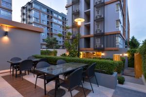 a patio with tables and chairs and buildings at The Grass Serviced Suites in Pattaya Central