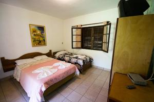 a bedroom with two beds and a window and a table at Pousada do Vale in Joanópolis