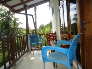 a balcony with two blue chairs and a table at Sky Garden Mini Hotel in Mirissa