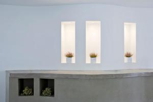 a concrete bench with potted plants on a white wall at Hippocampus Hotel in Kamari