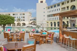 eine Terrasse mit Tischen und Stühlen und einem Pool in der Unterkunft Copthorne Lakeview Executive Apartments Dubai, Green Community in Dubai