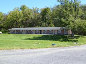 a building with two dogs in the grass in front of it at Lost River Motel in Lost City