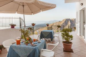 eine Terrasse mit Tischen, Stühlen und einem Sonnenschirm in der Unterkunft Hotel Bellavista in Maierà