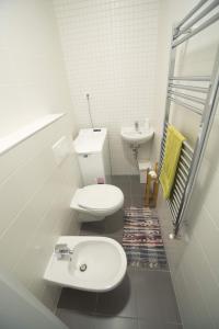 a white bathroom with a toilet and a sink at Holiday Home Podium in Eger