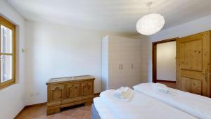 een slaapkamer met 2 bedden, een houten kast en een kroonluchter bij La Planüra 11 in Maloja