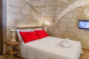 1 dormitorio con 1 cama con almohadas rojas y TV en LecceHome, en Lecce