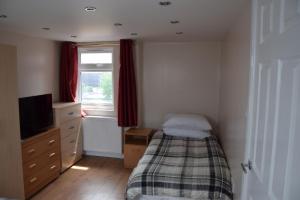 a bedroom with a bed and a tv and a window at 4 Bedroom Apartment & 2 Bedroom apartment in London