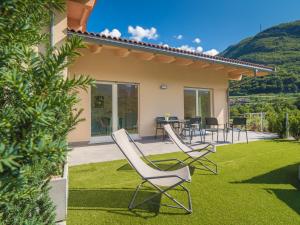 eine Terrasse mit Stühlen und einem Tisch auf dem Rasen in der Unterkunft La Gazza Ladra Apartments - Garda Chill Out in Drena